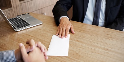 Man in suit shifting a document across the table to opposite man in business dress